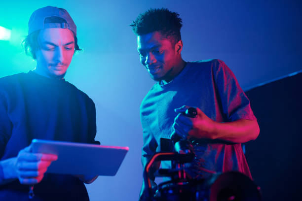 Director using digital tablet while discussing content with photographer in studio