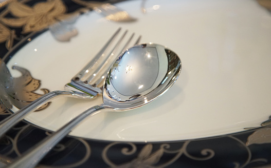 Spoon and fork tableware on a plate at the dining table