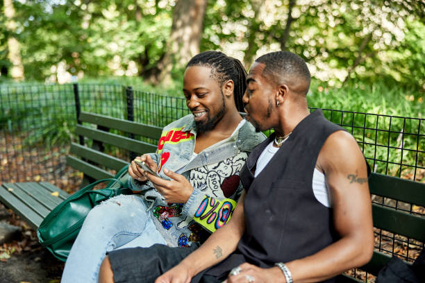 istock Black couple in 20s and 40s sitting on park bench, summer 1693359921