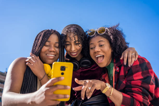 istock Multi-ethnic friends smiling while sharing a mobile outdoors 1693369788