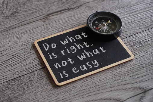 Closeup image of chalkboard with text DO WHAT IS RIGHT, NOT WHAT IS EASY and compass. Moral compass concept
