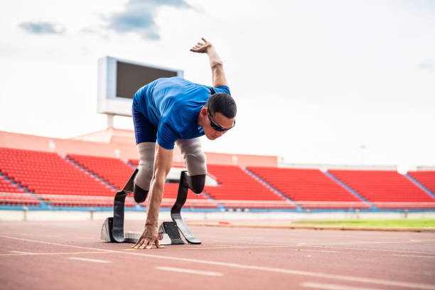 Asian para-athletes disabled with prosthetic blades running at stadium. Attractive amputee male runner exercise and practicing workout for Paralympics competition regardless of physical limitations