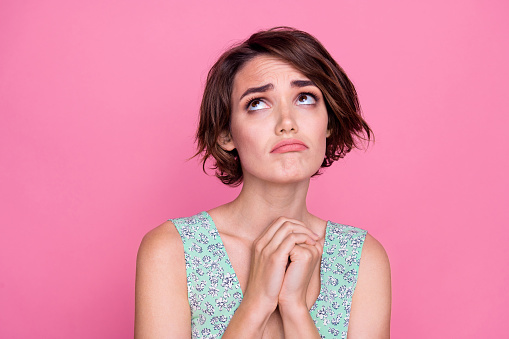 Closeup photo of beautiful young lady hands together miserable frustrated offended reaction look above isolated on pink color background.