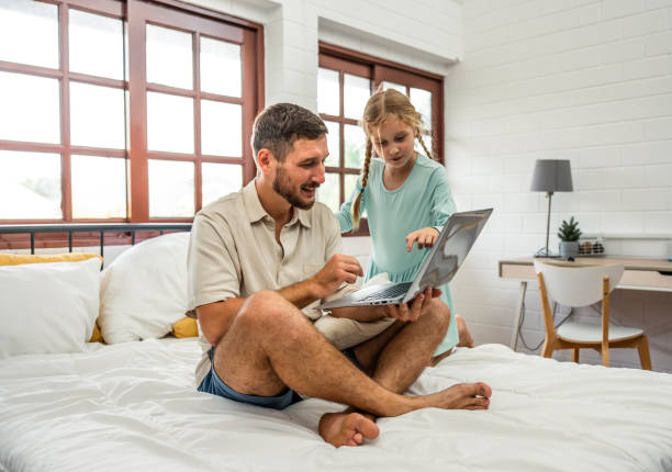 istock Caucasian attractive father using laptop computer with young daughter. Happy family, Handsome man parent feeling relax and enjoy working online at home with little cute girl on bed in bedroom in house 1693387153