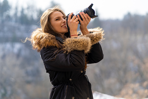 Young female tourist taking photos in nature in winter