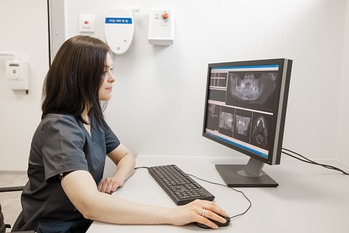 Doctor looks at the 3d scan of the jaw on the computer in office near X-ray room