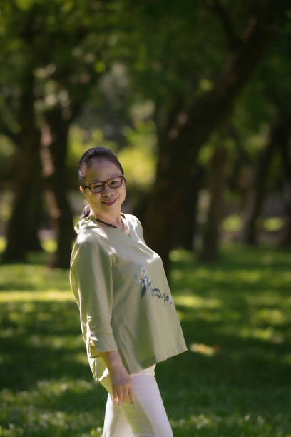 elderly asian woman over 60 years old in the park, independent and confident elderly woman. - independence lifestyles smiling years imagens e fotografias de stock