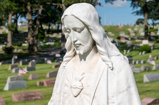 White stone cemetery statue of a serene Jesus with sacred heart. Head and shoulders closeup with no people and copy space.