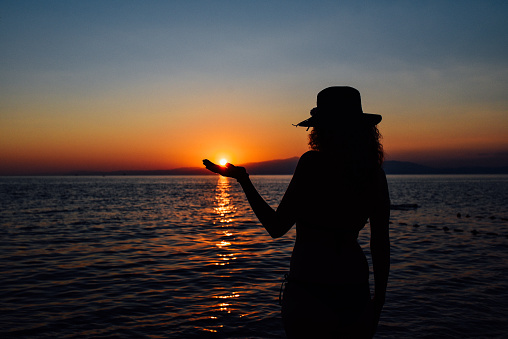 Silhouette of happy girl enjoying at sunset on the beach