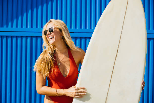 istock Surfer smiling on sunny beach with her surfboard and swimwear 1693431026