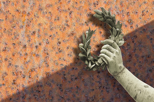 Hand holds a laurel wreath - concept image against a rusty metal background - Success and fame concept with copy space