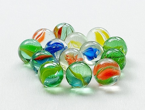 Marbles are children's toys from the 90s. Many marbles placed on a white background.