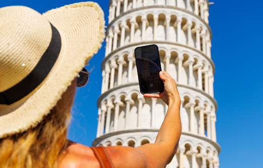 Woman tourist taking photo with her smartphone- Italy, Pisa tower