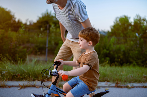 Father teaching his son to ride a bicycle.