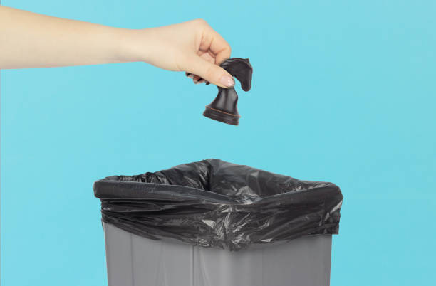 istock throwing a chess knight into a trash can, chess knight in hand in front of a trash can, leadership and competition, firing weak employees 1693437554