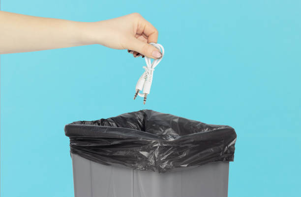 istock throw away TRRS audio jack, aux cable in trash can, cable in hand in front of trash can, wireless connection concept 1693437564