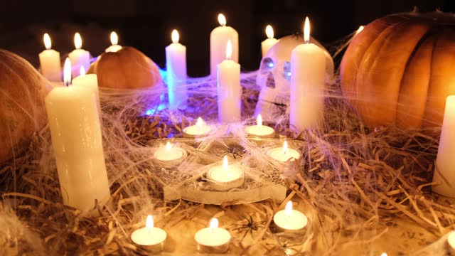 Horror background for seasonal holiday celebration with attributes of Halloween pumpkins, skull, pentagram and candles in cobweb.