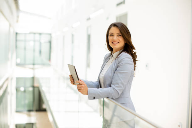 istock Young woman working on digital tablet in the office hallway 1693454456
