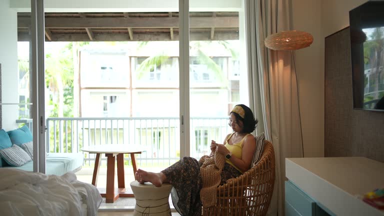 Young woman resting and enjoying crocheting from home in her apartment.