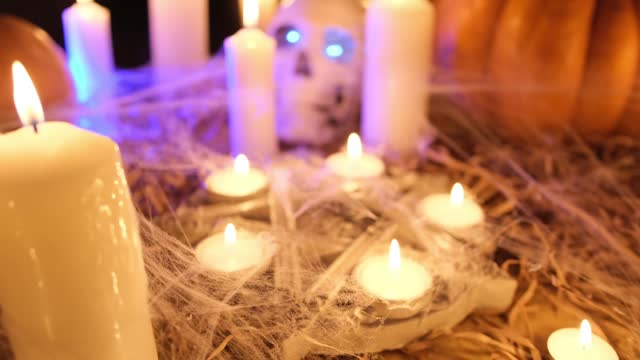 Close up tracking shot burning candles, magical pentagram with spiders, in cobweb among dry grass in darkness