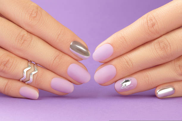 istock Close up womans hands with matte lavender nail design on purple background 1693462488