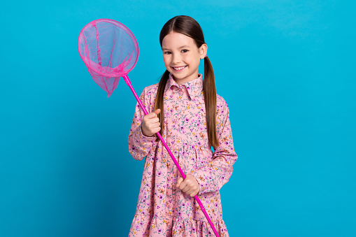 Portrait photo of satisfied young girl brunette hair hold butterfly net catch small animals playful kid isolated on blue color background.