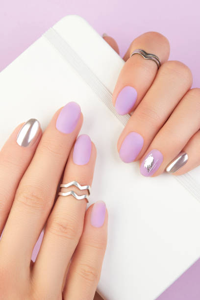 istock Close up womans hands with matte lavender and silver nails. Beauty treatment 1693467074