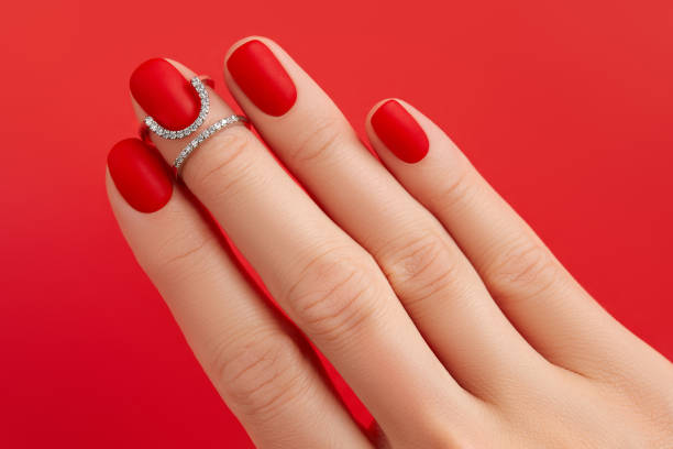 istock Close up womans hand with matt nails on red background. Manicure, pedicure design trends 1693475314