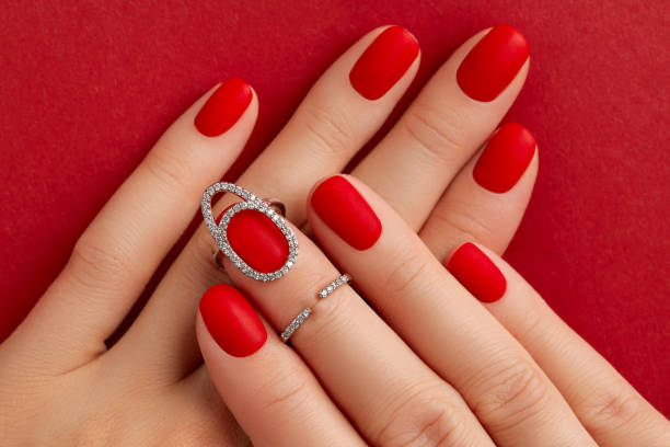 istock Close up womans hands with matt nails on red background. Manicure, pedicure design trends 1693476397