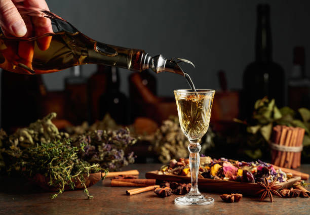 Yellow herbal liquor or mixture is poured from a vintage bottle into a glass. stock photo