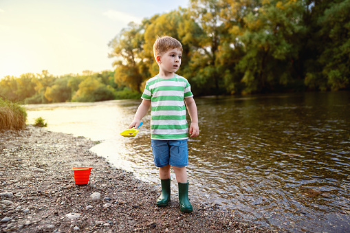 Little boy enjoying a carefree summer day by the river.