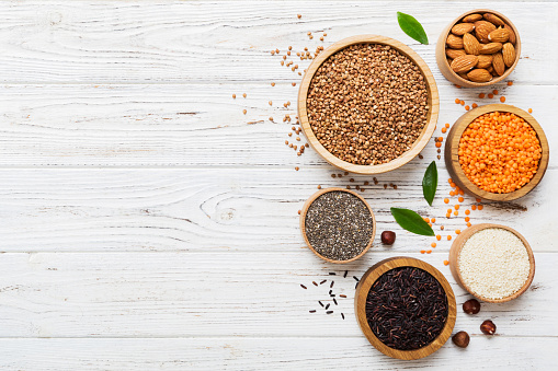 Various superfoods in smal bowl on colored background. Superfood as rice, chia, quinoa, lentils, nuts, sesame seeds, almonds. top view copy space.