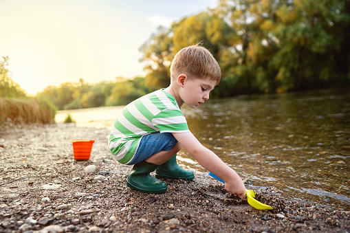 Little boy enjoying a carefree summer day by the river.