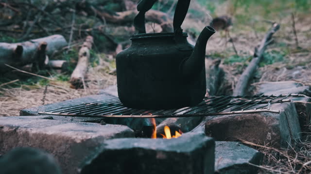 Smoked Teapot is Boiling Water Over Self-Made Tourist Stove in Nature