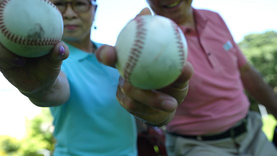 Elderly people over 60 years old played baseball in the park and recorded it on their mobile phones to show to their grandchildren