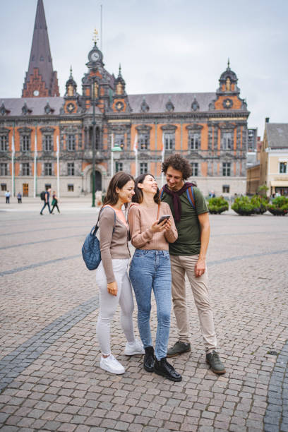 Three smiling tourists looking at a map while exploring the city of Malmo