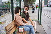Couple talking while sitting at the bus station waiting for the city bus
