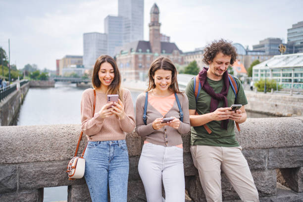 istock Three tourists looking at their mobile phones while standing on the city bridge 1693495357
