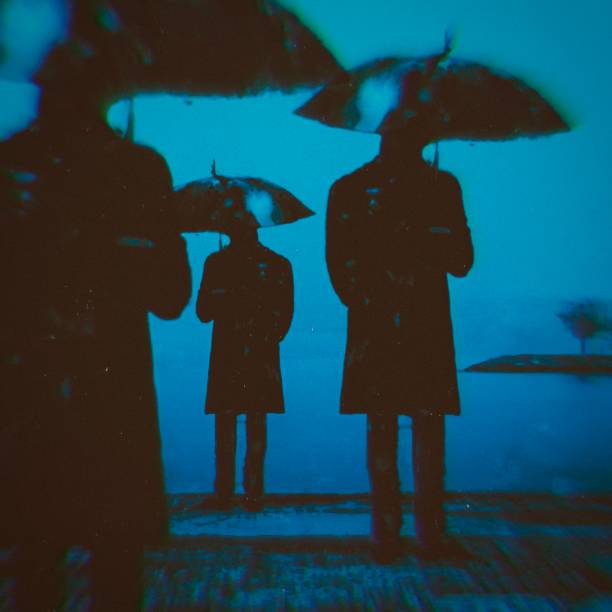 istock Three men with umbrellas on the coast. 1693505054
