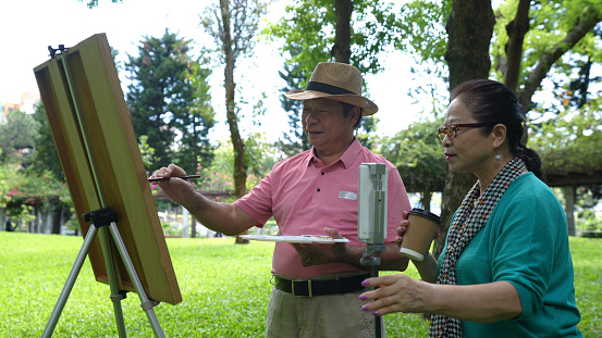 Elderly people over 60 years old paint in the park, use mobile phones to broadcast live broadcasts, and useing social media,