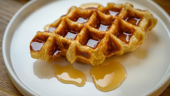 A plate of waffles, with butter and syrup.