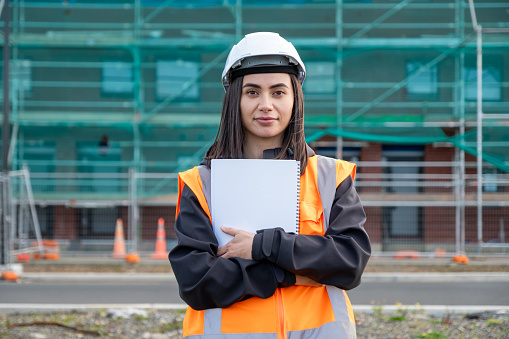 A female wearing protective clothing standing with note pad