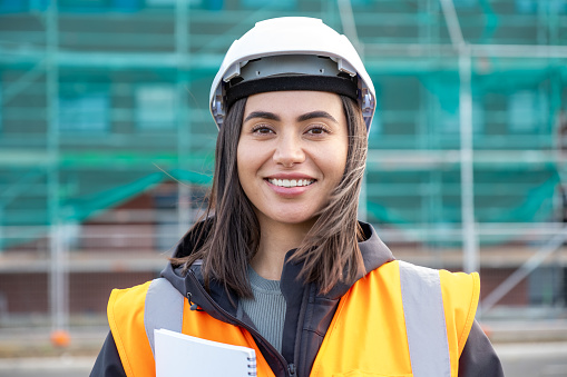 A portrait photo of female wearing a reflective vest and hardhat