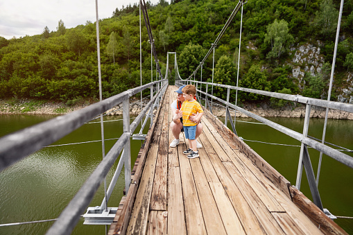 Mother and son on a suspension bridge over the Uvac river looking at beautiful nature scenery around them
