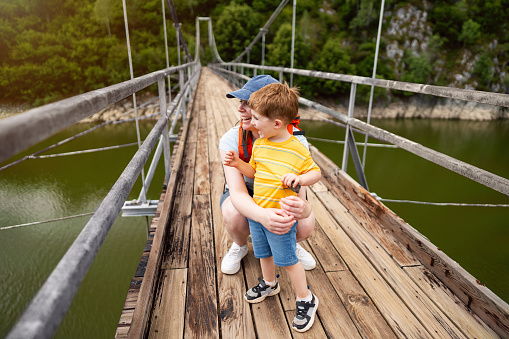 Mother and son on a suspension bridge over the Uvac river looking at beautiful nature scenery around them
