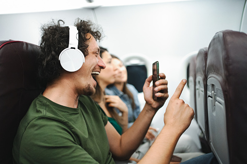 Men with wireless headphones listening to music on an airplane