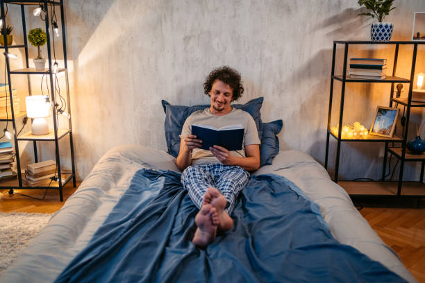 istock Young Man Reading A Book In The Bed At Night 1693536479