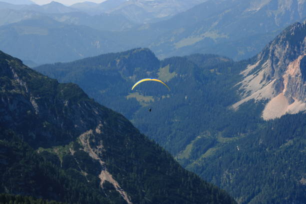 istock Alps. Dachstein Mountains. Austria. Paraplaner gliding in blue sky with view on Alpine mountains on paraplane 1693542367