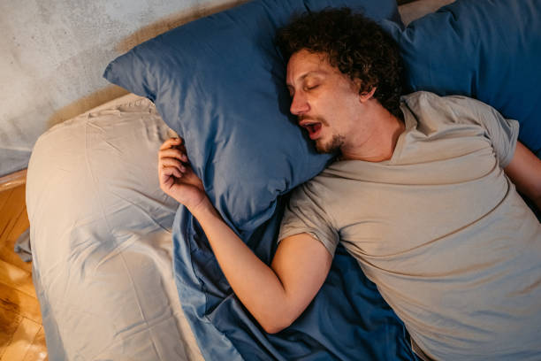 Young Man Snoring In The Bed At Night Handsome young man sleeping in the bed at night in his bedroom. Snoring and having breathing problems. human cardiopulmonary system audio stock pictures, royalty-free photos & images