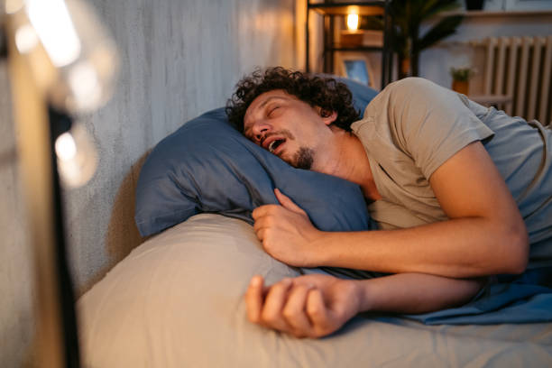 Young Man Snoring In The Bed At Night Handsome young man sleeping in the bed at night in his bedroom. Snoring and having breathing problems. human cardiopulmonary system audio stock pictures, royalty-free photos & images